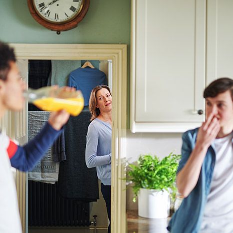 Mother looking in mirror at two teenagers