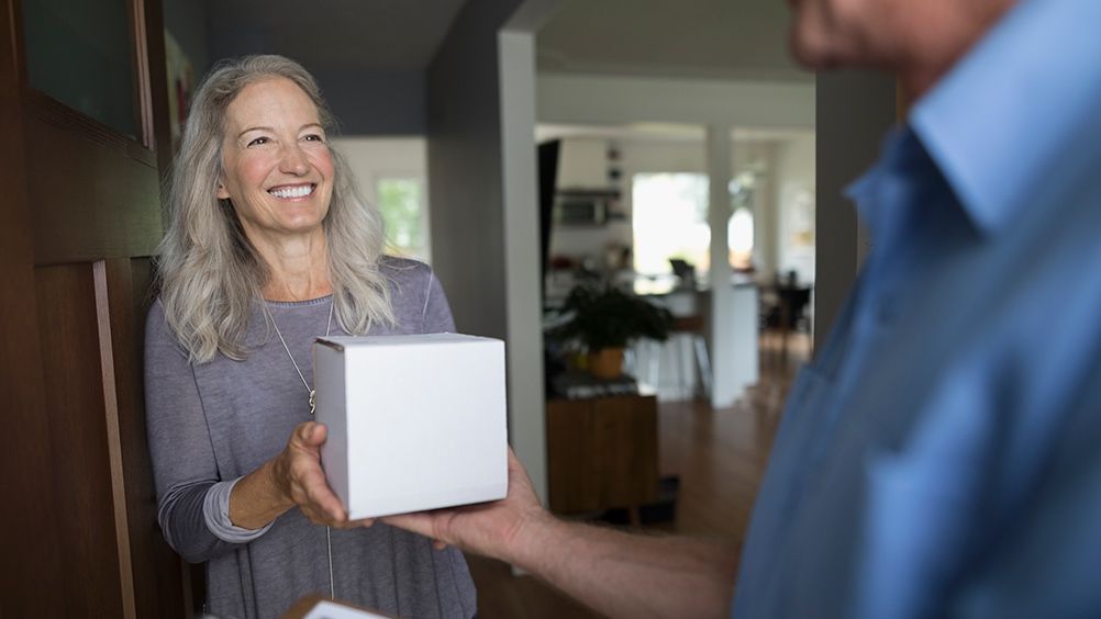 Lady smiling at home holding home screening kit