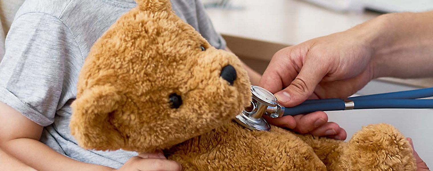 Someone holding a stethoscope to a teddy bear