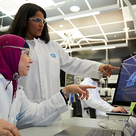 Two Pfizer employees pointing at laptop