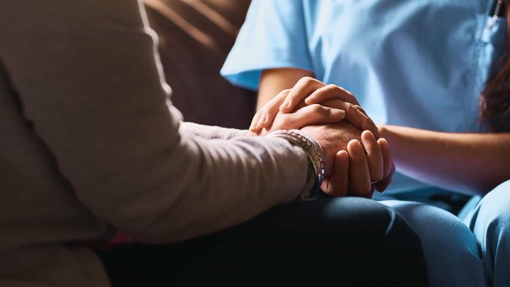 Close-up of a physician holding hands with a patient