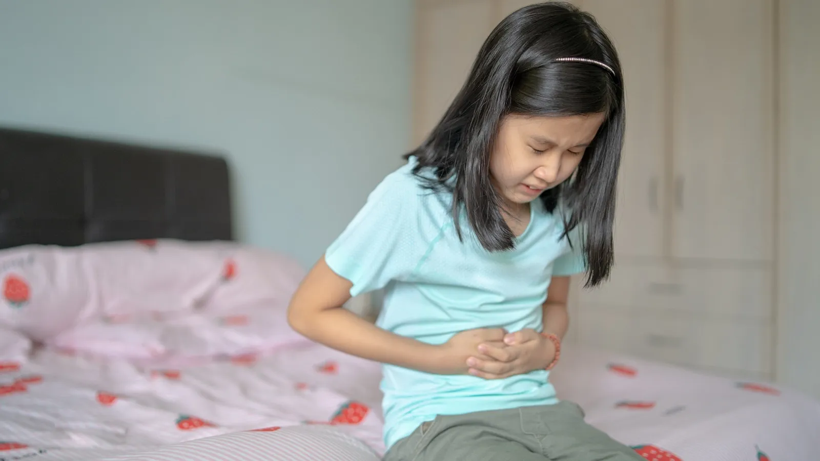 image of child holding her stomach in pain