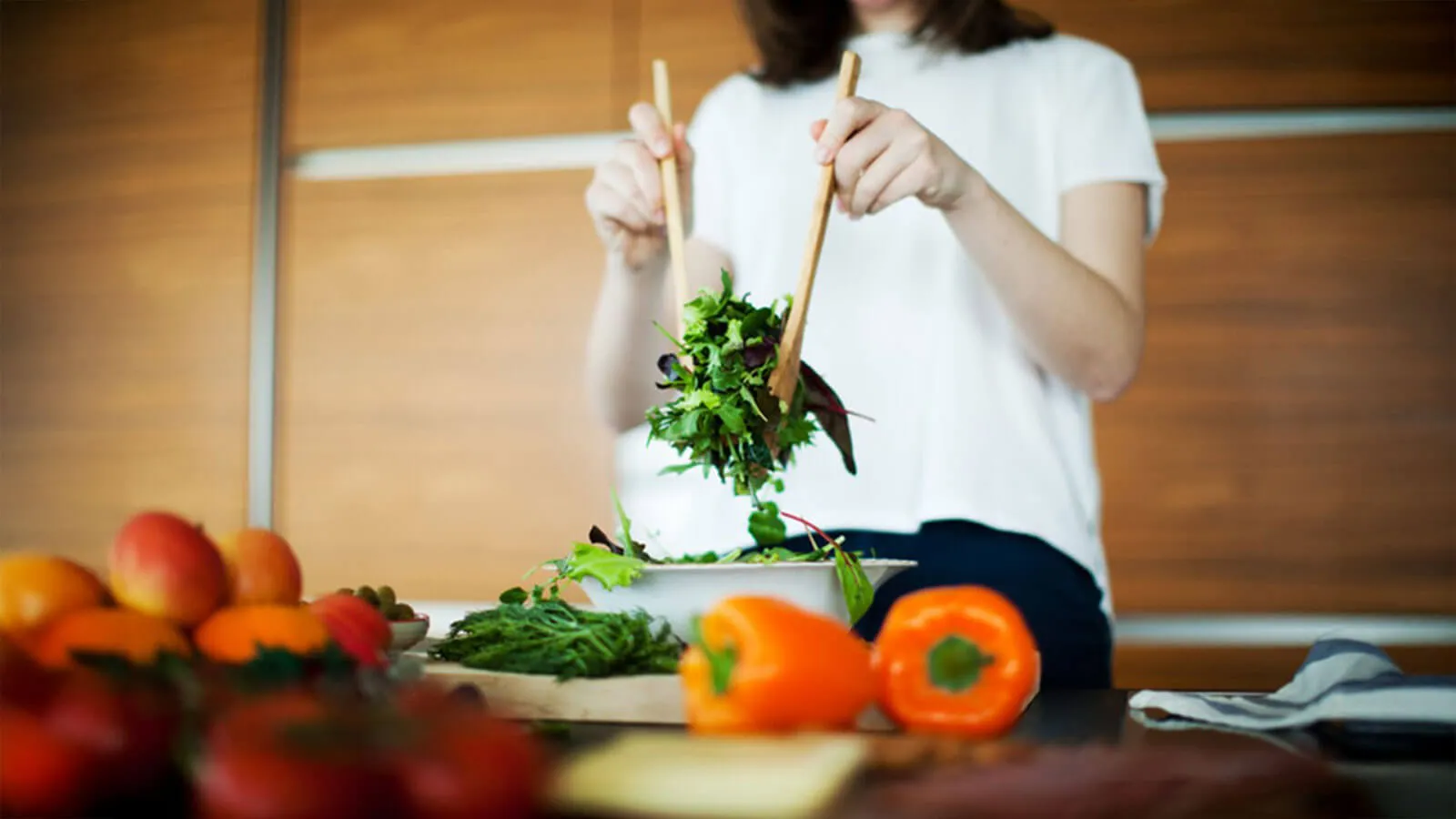 Person tossing salad in a bowl