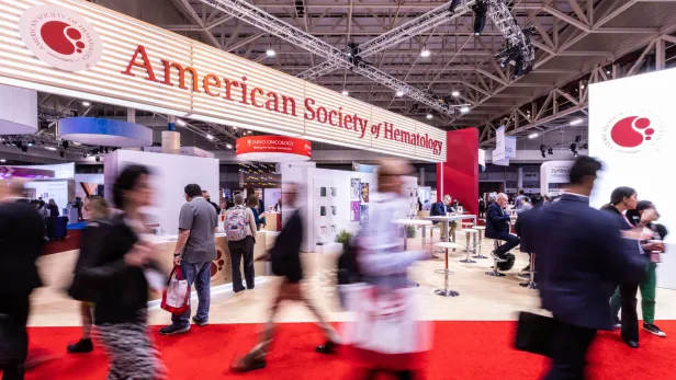 people walking by in front of the American Society of Hematology booth