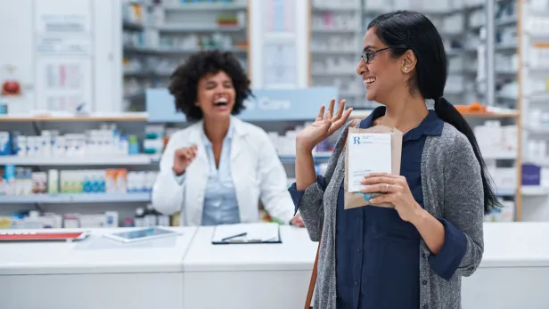 Shot of a mature woman waving to a pharmacist in a chemist